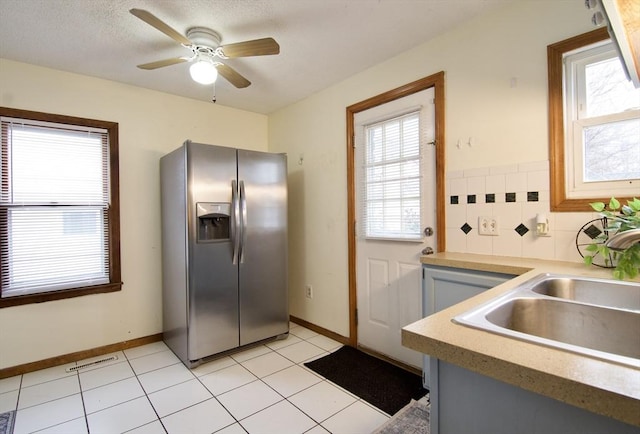 kitchen featuring a wealth of natural light, stainless steel refrigerator with ice dispenser, a sink, and visible vents