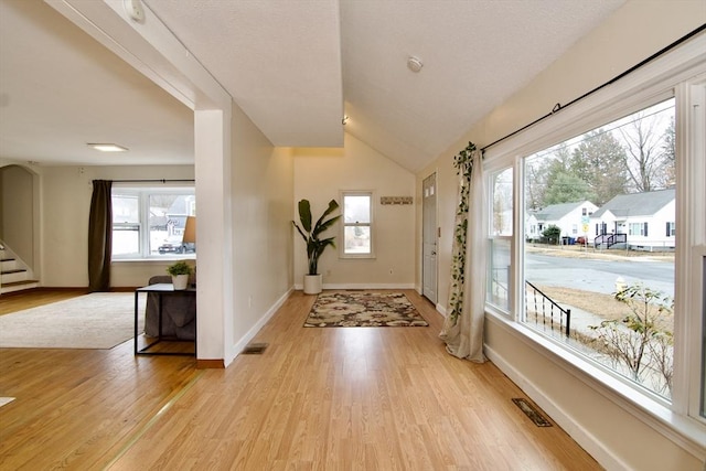 foyer entrance featuring baseboards, stairway, visible vents, and light wood-style floors