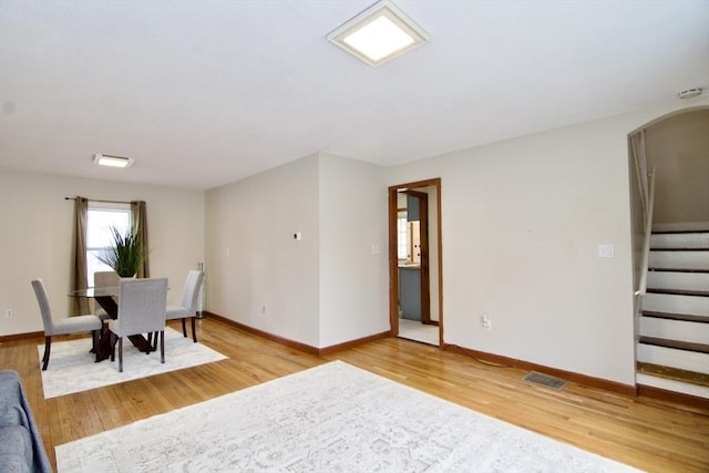 dining area featuring baseboards, stairway, visible vents, and light wood-style floors