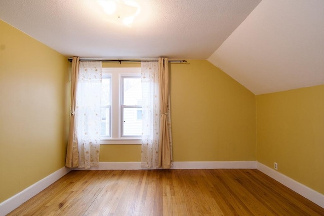 bonus room featuring light wood finished floors, baseboards, and vaulted ceiling