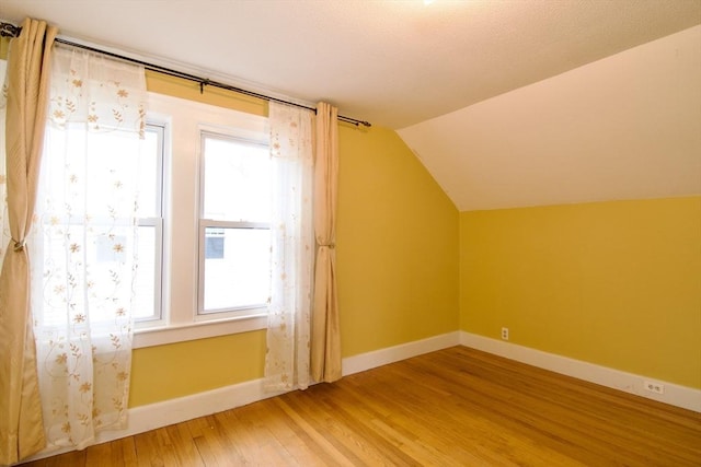 additional living space with vaulted ceiling, light wood-style flooring, and baseboards