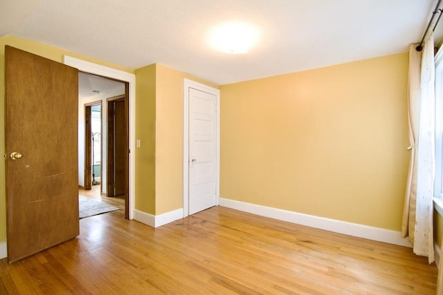 spare room with light wood-style floors and baseboards