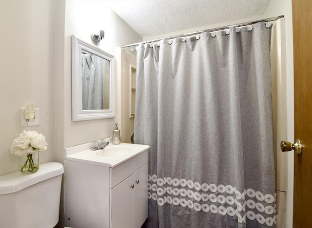 full bathroom featuring toilet, curtained shower, a textured ceiling, and vanity