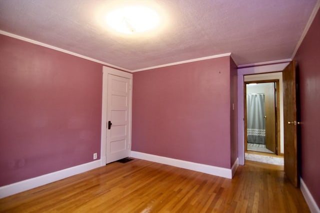 spare room with crown molding, wood finished floors, and baseboards