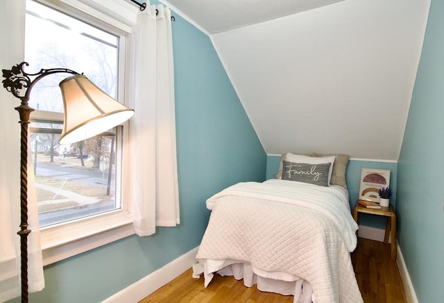 bedroom with lofted ceiling, wood finished floors, and baseboards