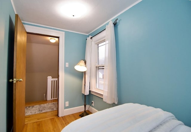 bedroom featuring light wood-style floors, baseboards, and crown molding