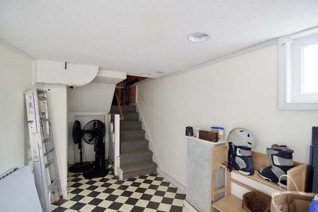 stairs with ornamental molding, a textured ceiling, and tile patterned floors