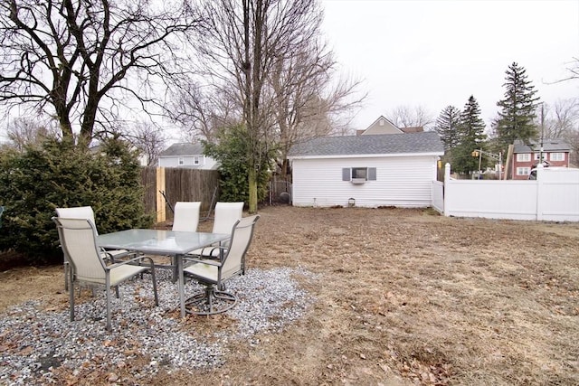 view of yard with fence, an outdoor structure, and outdoor dining space