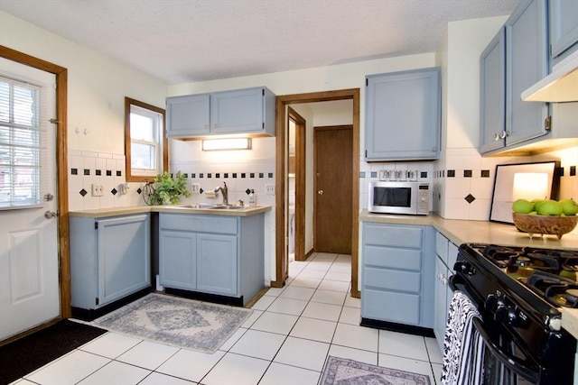 kitchen featuring light countertops, white microwave, black range with gas stovetop, and blue cabinets