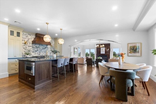 197 Winchester St Unit 197, Brookline, MA 02446 - dining area featuring arched walkways, crown molding, a brick fireplace, dark wood-type flooring, and recessed lighting