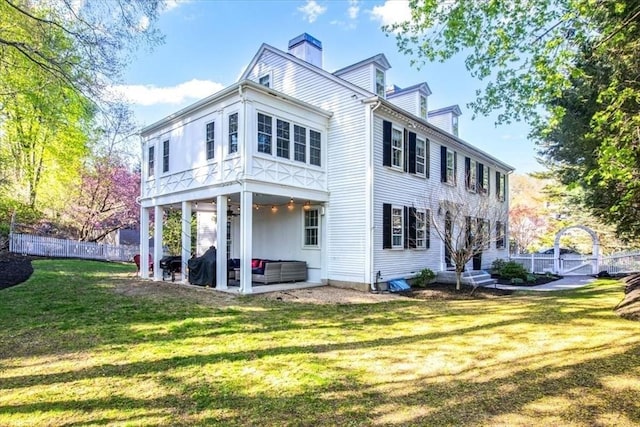 back of house featuring fence, a chimney, a ceiling fan, a patio, and a yard