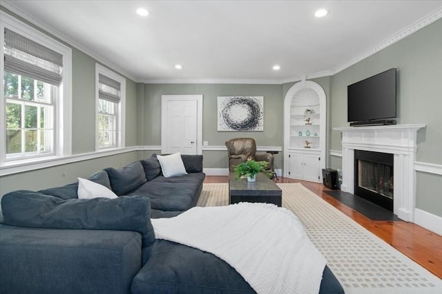 living room with a fireplace with flush hearth, ornamental molding, recessed lighting, and wood finished floors