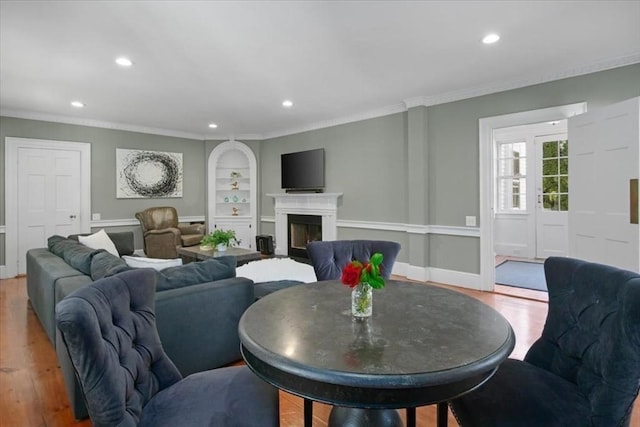 living area with crown molding, built in shelves, recessed lighting, and wood finished floors