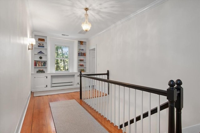 interior space featuring crown molding, built in features, baseboards, an upstairs landing, and light wood-style flooring