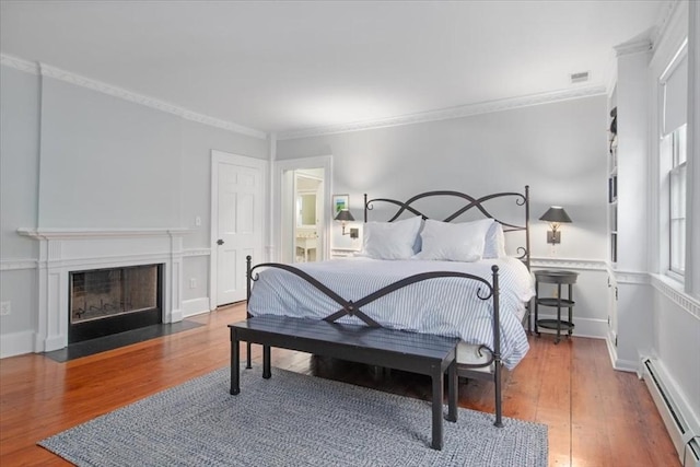 bedroom with ornamental molding, wood finished floors, and a baseboard radiator