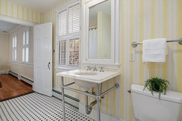 bathroom featuring baseboards, baseboard heating, and toilet
