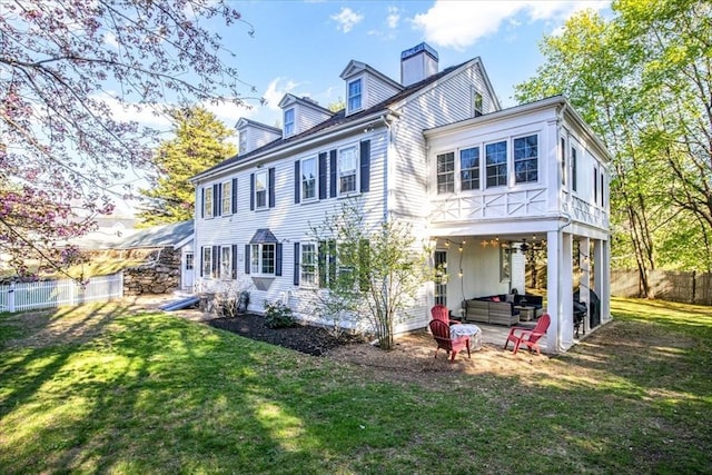 rear view of house with a yard, a chimney, and a fenced backyard