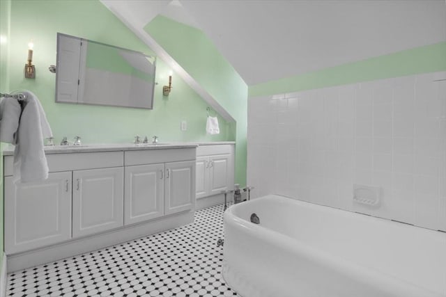 bathroom featuring double vanity, lofted ceiling, a sink, and a freestanding bath