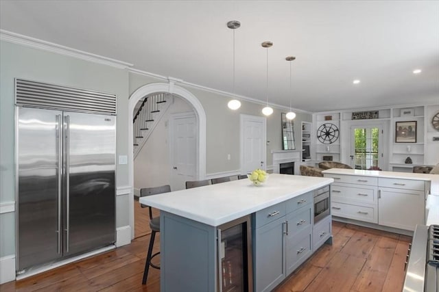 kitchen with crown molding, dark wood-style flooring, built in appliances, and wine cooler