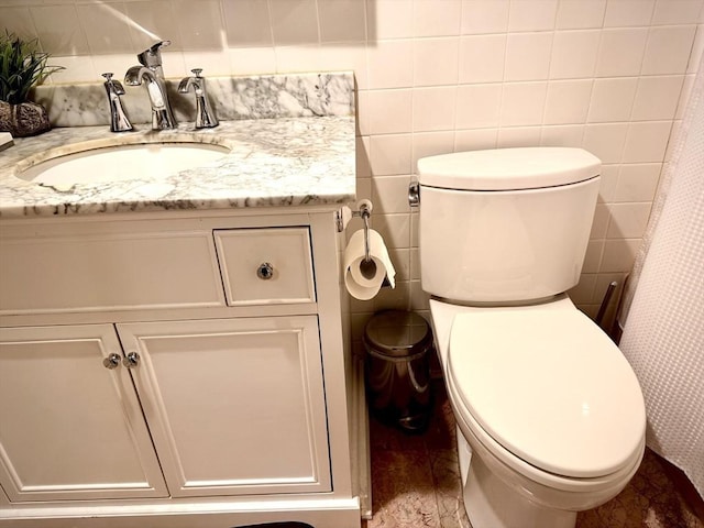 bathroom with vanity, toilet, and tile walls