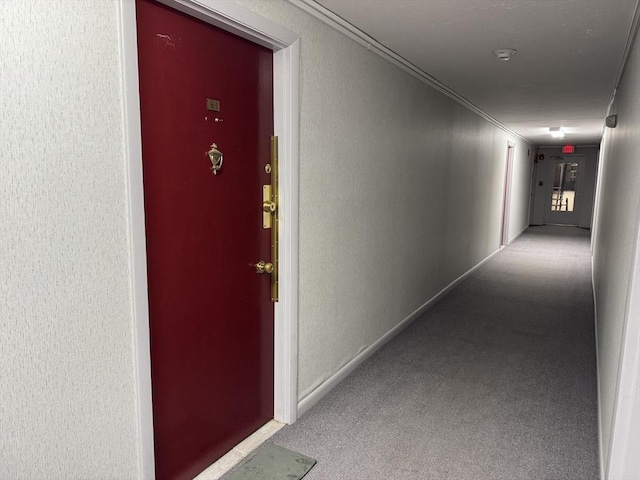 hallway with carpet, crown molding, a textured wall, and baseboards