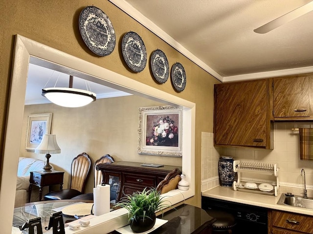 kitchen featuring a sink, ornamental molding, black dishwasher, backsplash, and light countertops