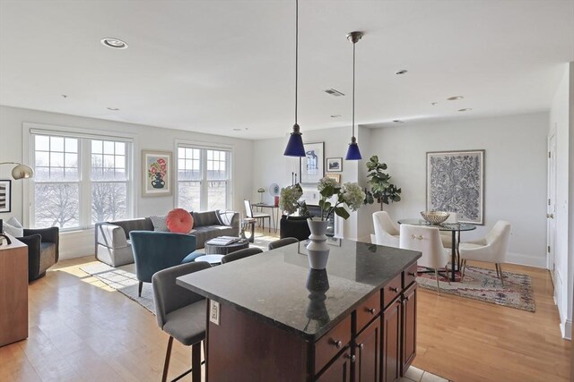 1306 Columbia Rd Unit 5C, Boston, MA 02127 - kitchen featuring pendant lighting, a kitchen island, open floor plan, light wood-style floors, and a breakfast bar area