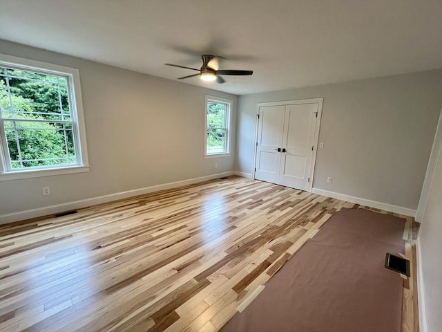 unfurnished bedroom featuring light wood-style floors, baseboards, a closet, and a ceiling fan