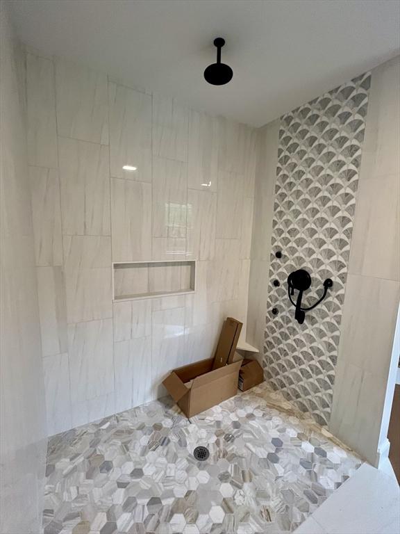bathroom featuring tiled shower and tile walls