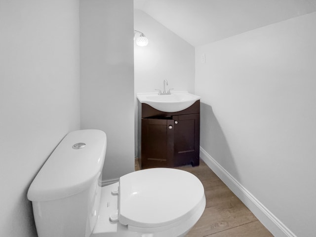 bathroom with lofted ceiling, vanity, and toilet