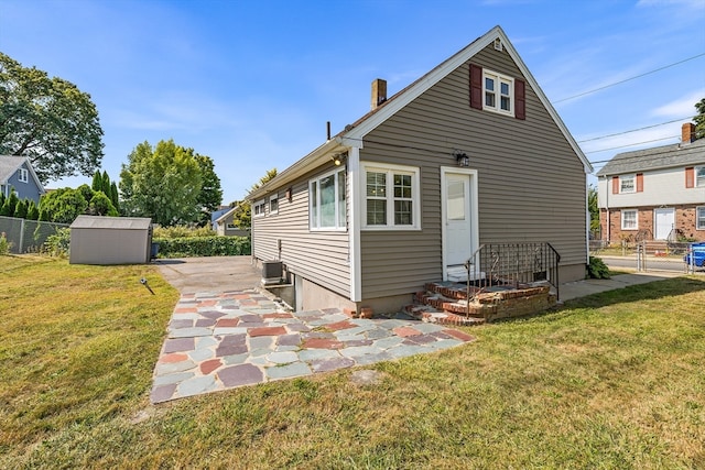 back of house featuring a storage unit, a yard, and cooling unit