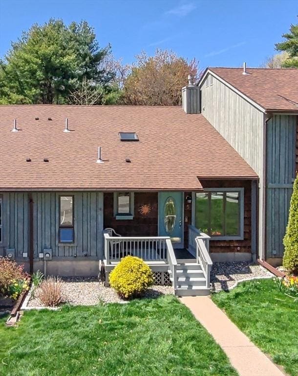 view of front of home with covered porch, board and batten siding, a shingled roof, and a front yard