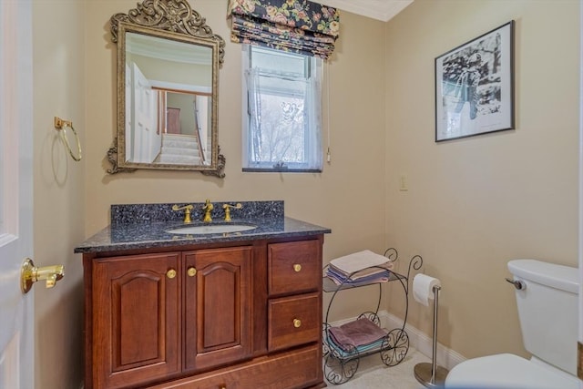 half bathroom with vanity, ornamental molding, baseboards, and toilet