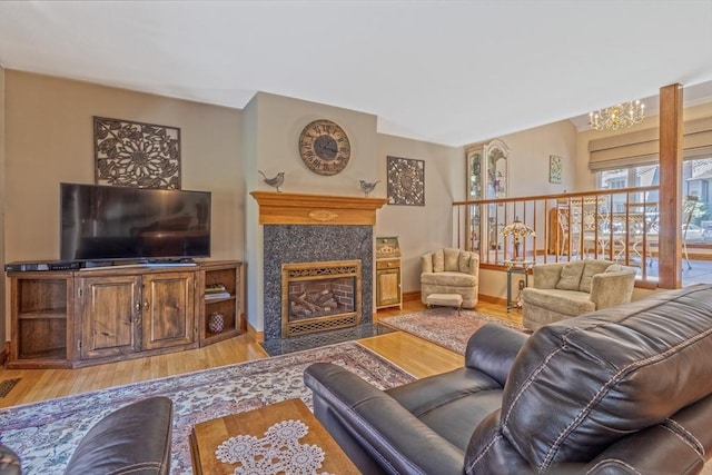 living area with light wood-style floors, a chandelier, and a fireplace