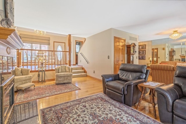 living room with visible vents, wood finished floors, stairway, baseboards, and a chandelier