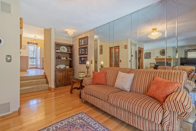 living area with stairway, light wood-style flooring, a chandelier, and visible vents