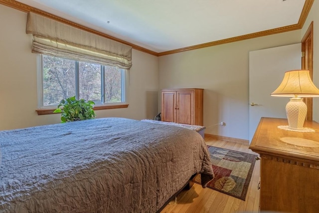 bedroom with crown molding, light wood-style flooring, and baseboards