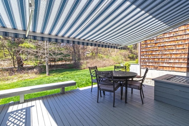 wooden terrace featuring outdoor dining area and a yard