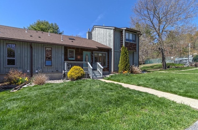 rear view of property with board and batten siding, a lawn, and covered porch