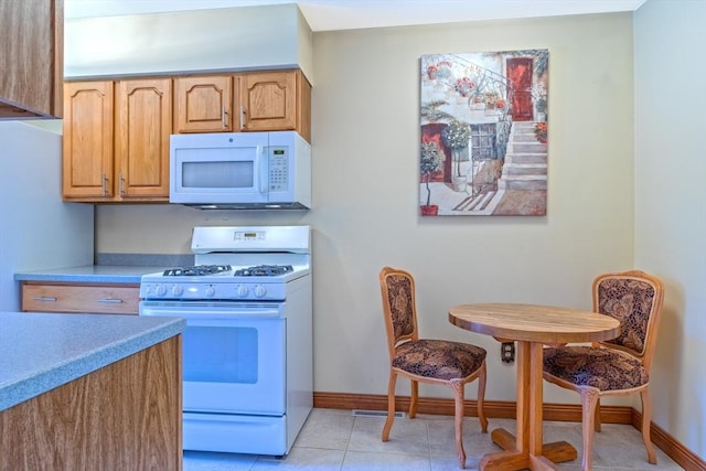 kitchen with white appliances, light tile patterned flooring, baseboards, and light countertops