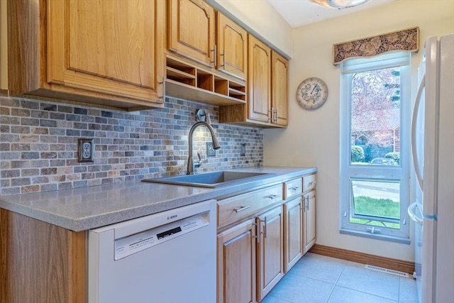 kitchen featuring backsplash, a sink, light tile patterned floors, light countertops, and white appliances