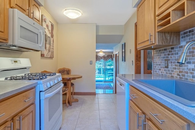 kitchen featuring tasteful backsplash, a sink, light tile patterned floors, baseboards, and white appliances