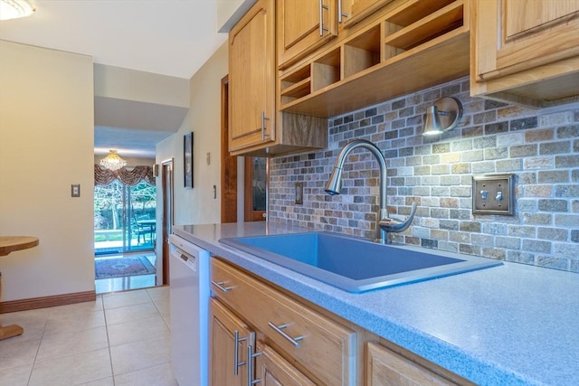 kitchen with white dishwasher, a sink, light countertops, decorative backsplash, and light tile patterned floors