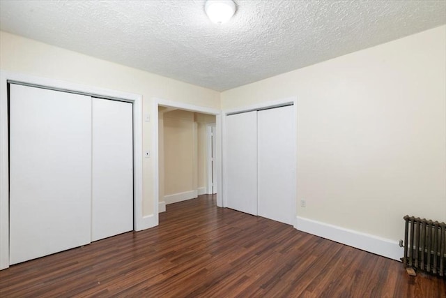 39-41 Arlington St, Methuen, MA 01844 - unfurnished bedroom with radiator heating unit, two closets, wood finished floors, baseboards, and a textured ceiling