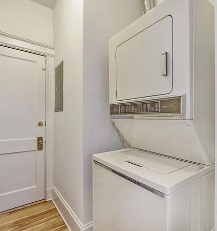 68 Parkman St Unit 3, Brookline, MA 02446 - washroom with stacked washer and clothes dryer, electric panel, and light wood-type flooring