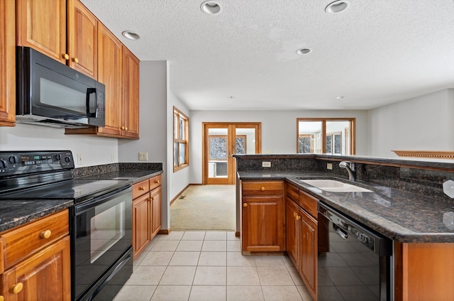 kitchen featuring light colored carpet, a textured ceiling, black appliances, dark stone countertops, and sink