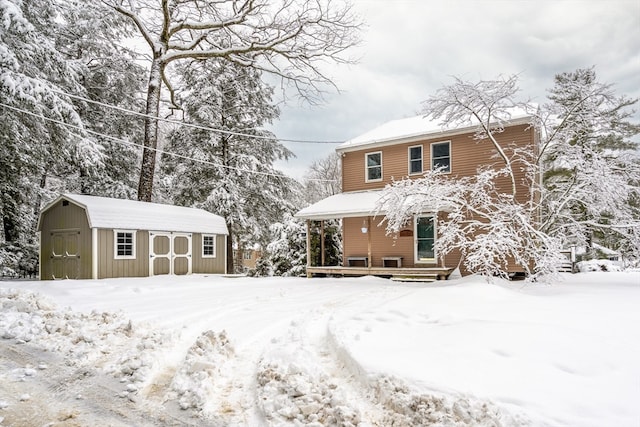 snow covered rear of property featuring a shed