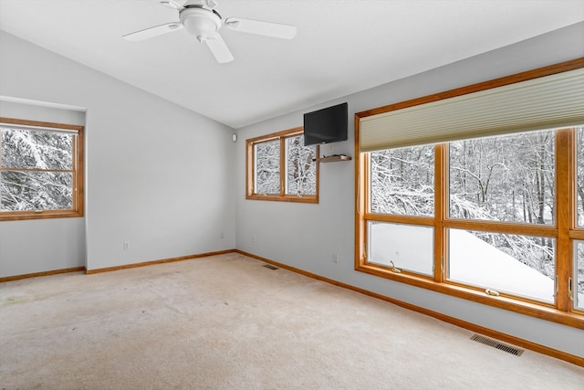 spare room featuring light carpet, vaulted ceiling, and ceiling fan