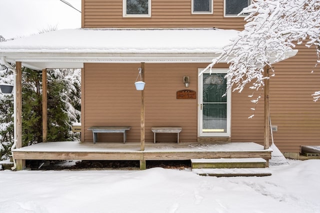 snow covered property entrance featuring a deck