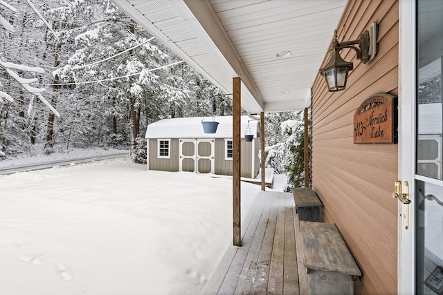 snow covered patio featuring a storage shed